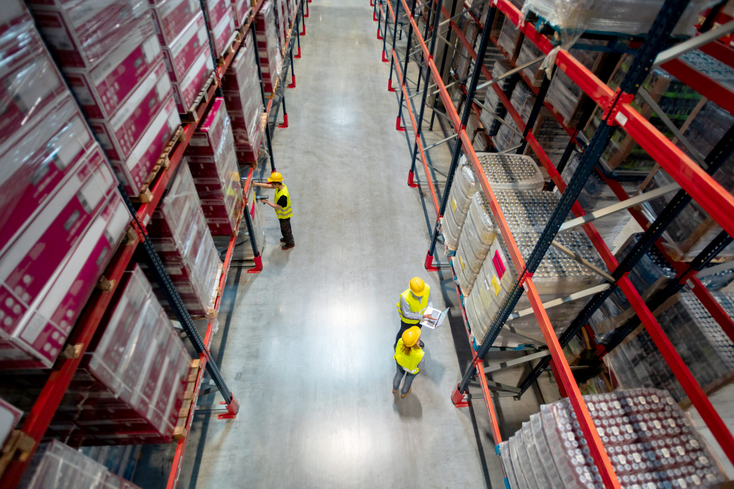 Warehouse managers consult plans using laptop, above view